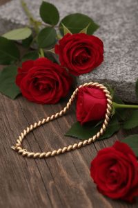 gold necklace placed by roses